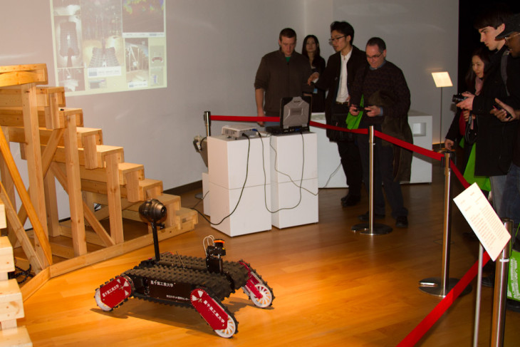 a faculty member examines a robot displayed at a Japanese technical institute