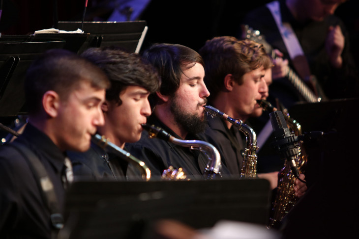 Four saxophonists in a line, performing