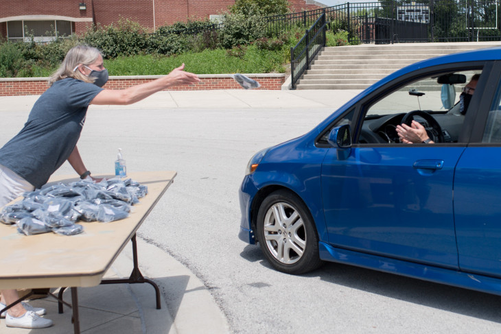 Worker tosses masks to man in car on mask pickup day