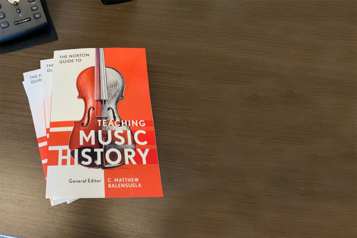 Stack of books entitled "The Norton Guide to Teaching Music History" on a desk