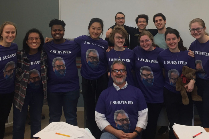 Class standing behind professor all wearing shirts with his face on them