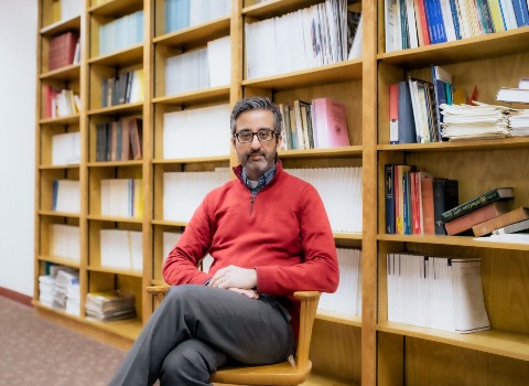 Nahyan Fancy sitting in an office with multiple shelves of reading material in the background