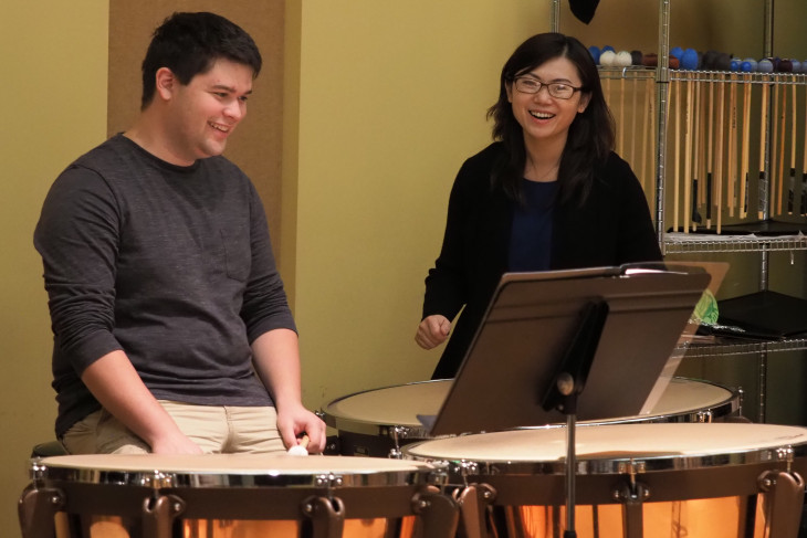 A man and woman laughing while playing timpani