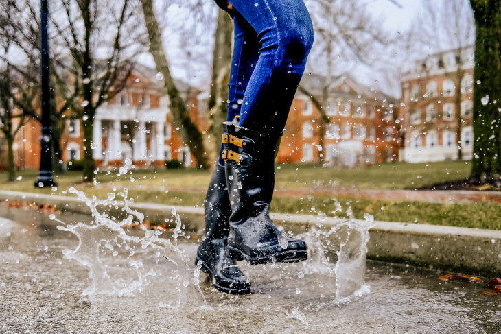 Feet stomping in puddles with campus buildings in the background.