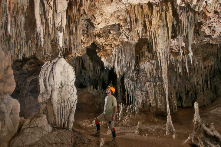Philip Rykwalder stands at the bottom of a deep cave covered in stalactites and stalagmites