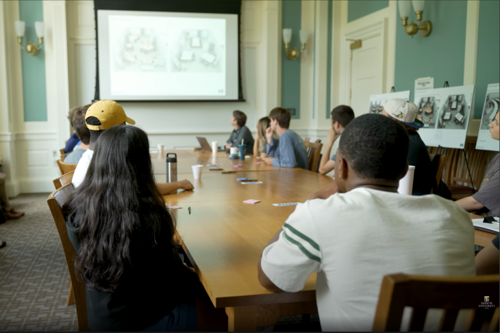 Students and Faculty around the table reviewing architecture information
