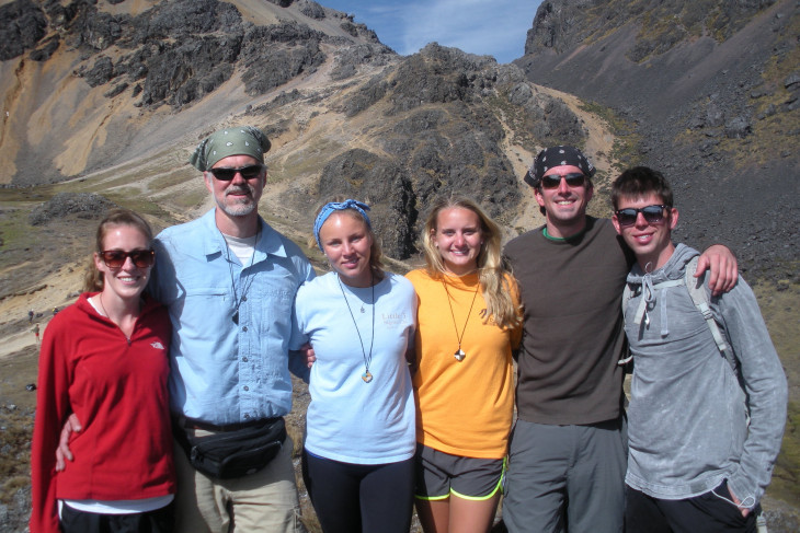 Group of 6 people posing in front of rugged mountains