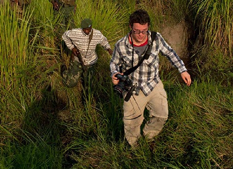  Ben Solomon '10 walking through tall grass while reporting in west Africa