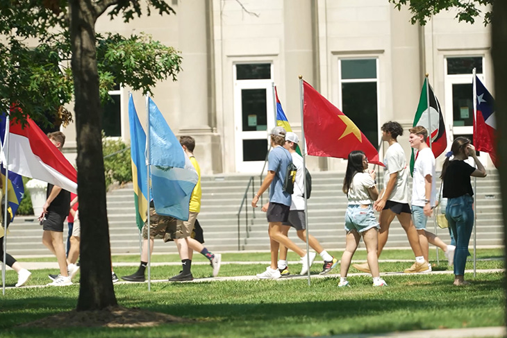Students walking outside beside international flags