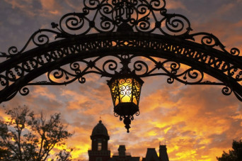 Arch with hanging lantern during sunset with East College backdrop