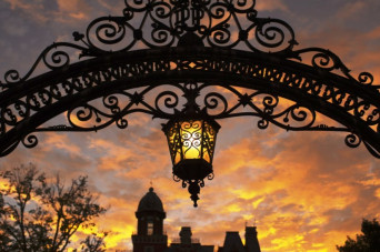 Arch with hanging lantern during sunset with East College backdrop