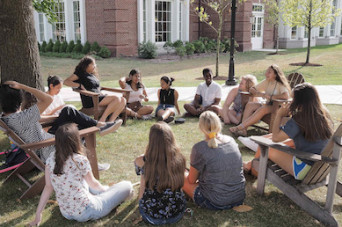 Students sitting in a circle for a class held outdoors