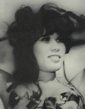 Lyn May by Thomas Glassford (Depicts a black and white photograph of a woman wearing a bikini while her arms are raised and holding her hair up)
