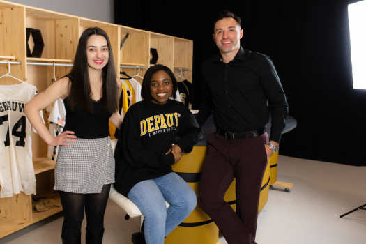 Students posing in front of a wooden locker with jerseys