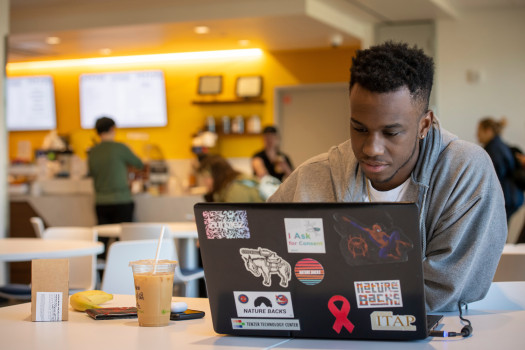 Student working on a laptop while having a snack at Roy O. West 