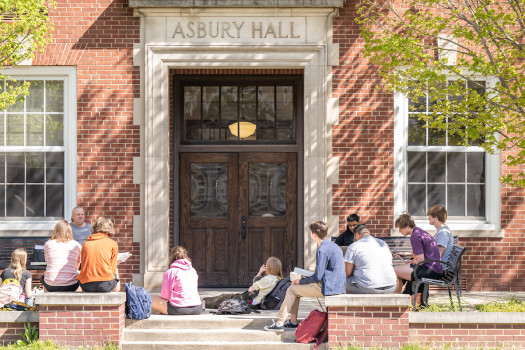 Student attending an outside class in front of the main entrance to Asbury Hall