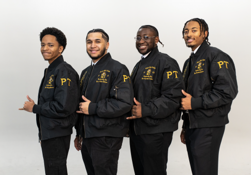 4 members of Alpha Phi Alpha Fraternity, Inc in a line with their Greek hand symbol