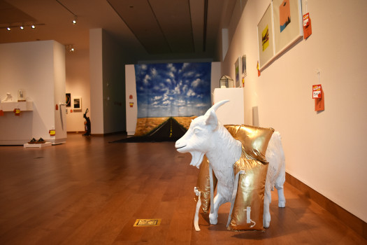 a white goat statue wearing a gold life jacket is to the right hand side with other objects visible in the background with price tags