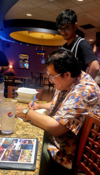 A student anticipates Eduardo Corral's autograph after a shared lunch.