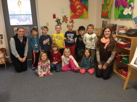 Two DePauw students sitting with a group of elementary school children.