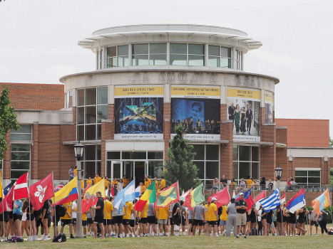 Student assembled on move-in day among the country flags in front of the Green Center