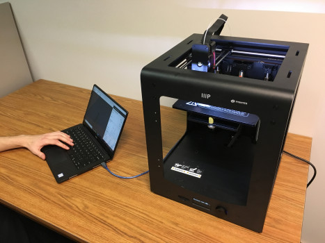 A 3D printer connected to a laptop