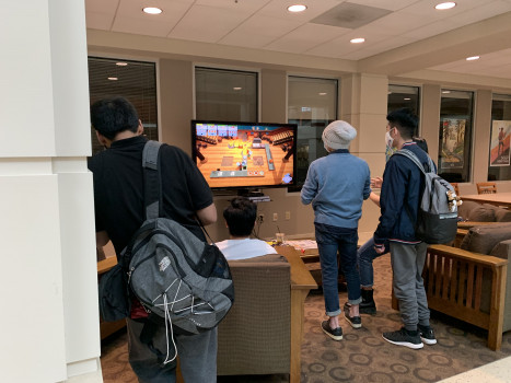 Students gathered around a monitor playing Over Cooked. 