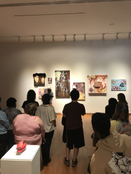 People walking through the 2023 Senior Thesis exhibit in the Visual Arts Gallery on the 1st floor of the Richard E. Peeler Art Center