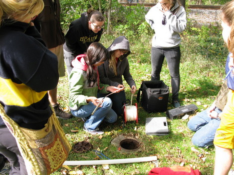 Students using a water-level indicator to measure depth to the water table in a local monitoring well.