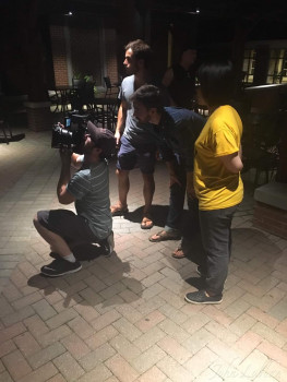 three people at night another person kneeling behind video camera