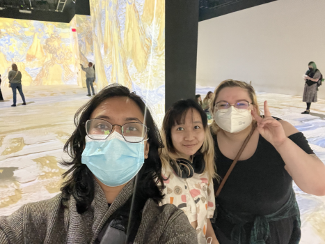 Three students in front of a digital display of Van Gogh's art