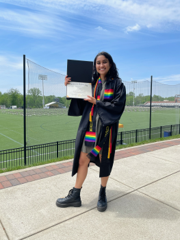 student in regalia holding. diploma