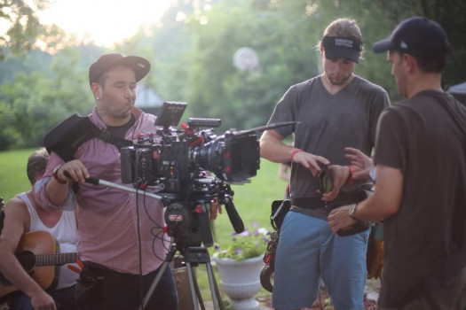 three people standing one behind video camera