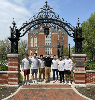 The council hugging in front of the East College building with their advisor