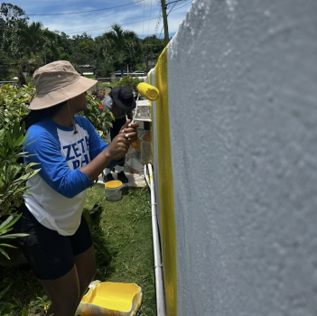 Zeta member painting a community wall