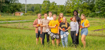 Students posing together with a thank you sign at the Ullem Farm
