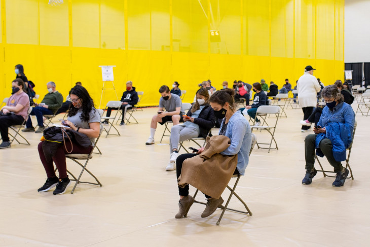 People in chairs awaiting their turn to get a vaccine.