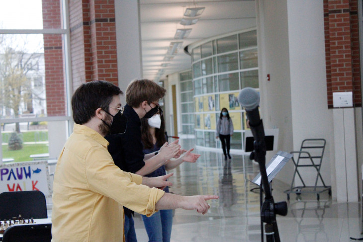 2 men and a woman clapping in front of microphones