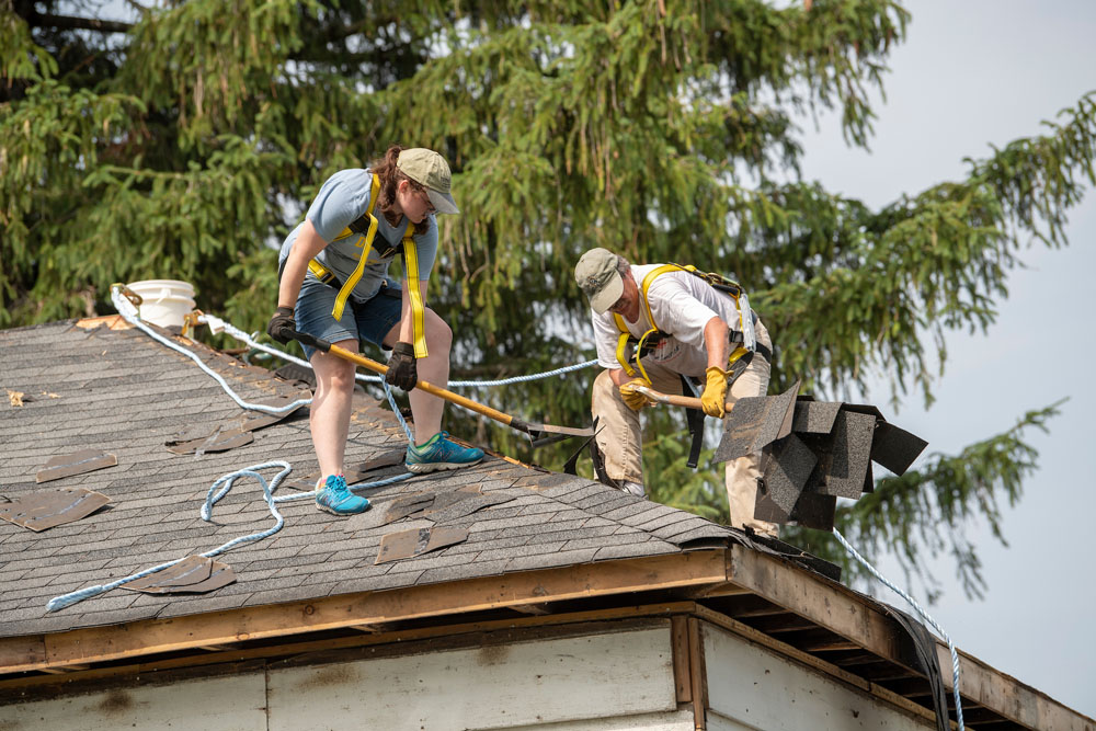 Cecilia and Prof. Mills work on removing shingles from the old farmhouse.