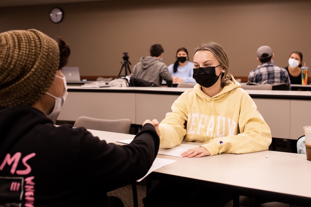 Students shake hands during a speed interview session.