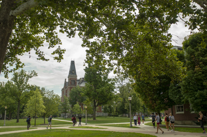 Students walking through DePauw campus with East College in the background