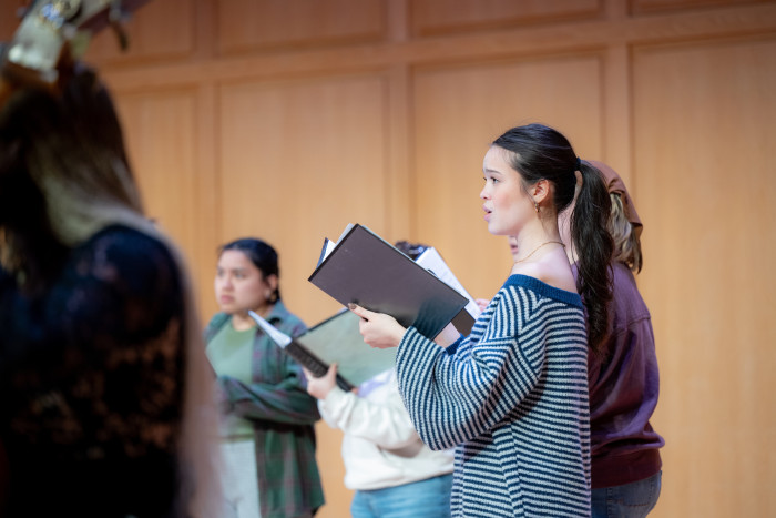 Students practicing for choral performance holding sheet music 