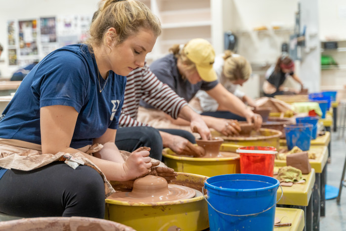 Students throw bowls on pottery wheels.