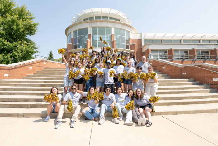 Students on the Green Center steps cheering with Pom Poms