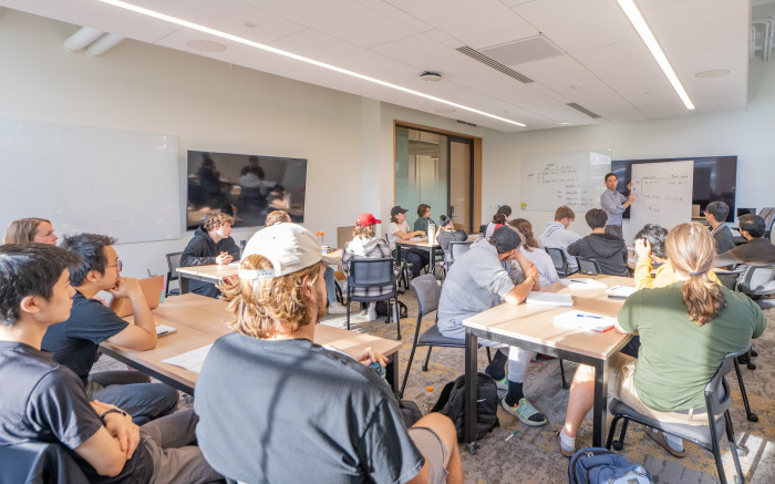 Students sit in classroom while professor teaches