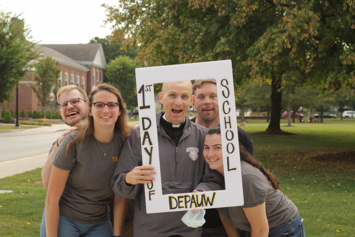 Missionaries posing with Father Hollowell behind a 1st day of school sign