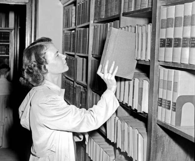 Jane Noble Luljak takes a book down from a shelf. 