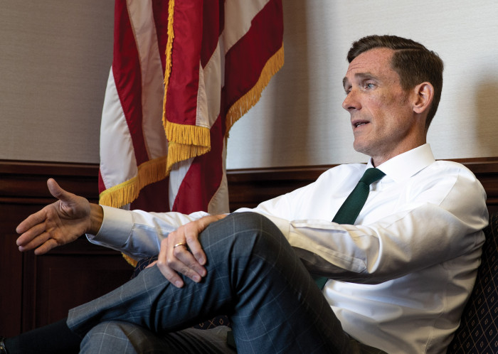 Judge J.P. Hanlon sits on couch near a U.S. flag