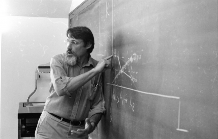 Ralph Gray at a chalkboard while teaching a clsss
