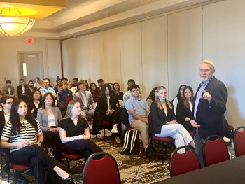 Students from the Spring 2025 pitch competition seated listening to Steve Fouty announcing the winner